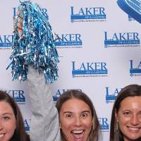 Group of alumni posing together raising hands